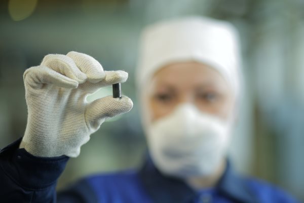 A worked from Kazatomprom holds a uranium pellet between thumb and forefinger